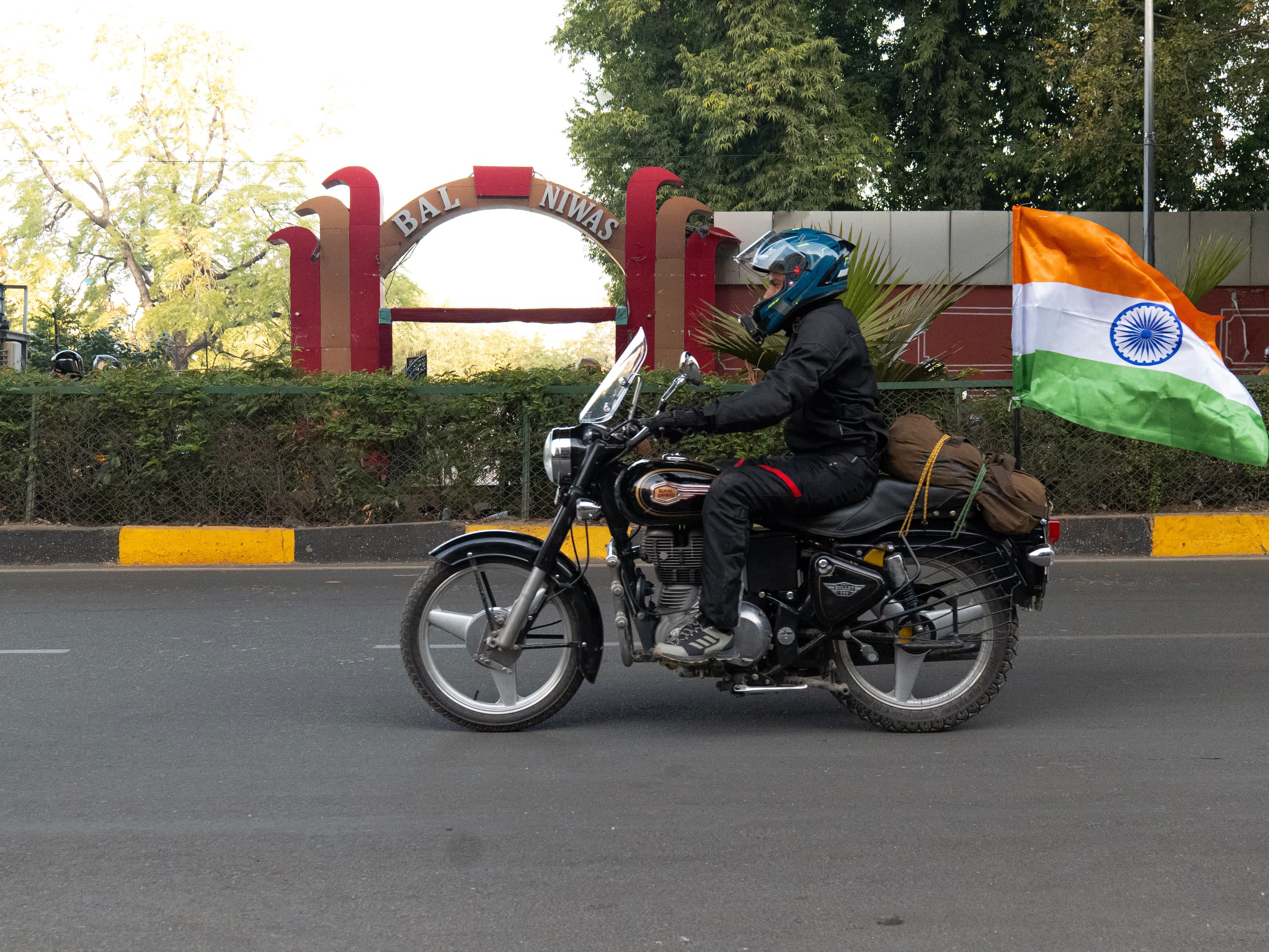 Rider passing a city gate with the national flag flying from the pillion