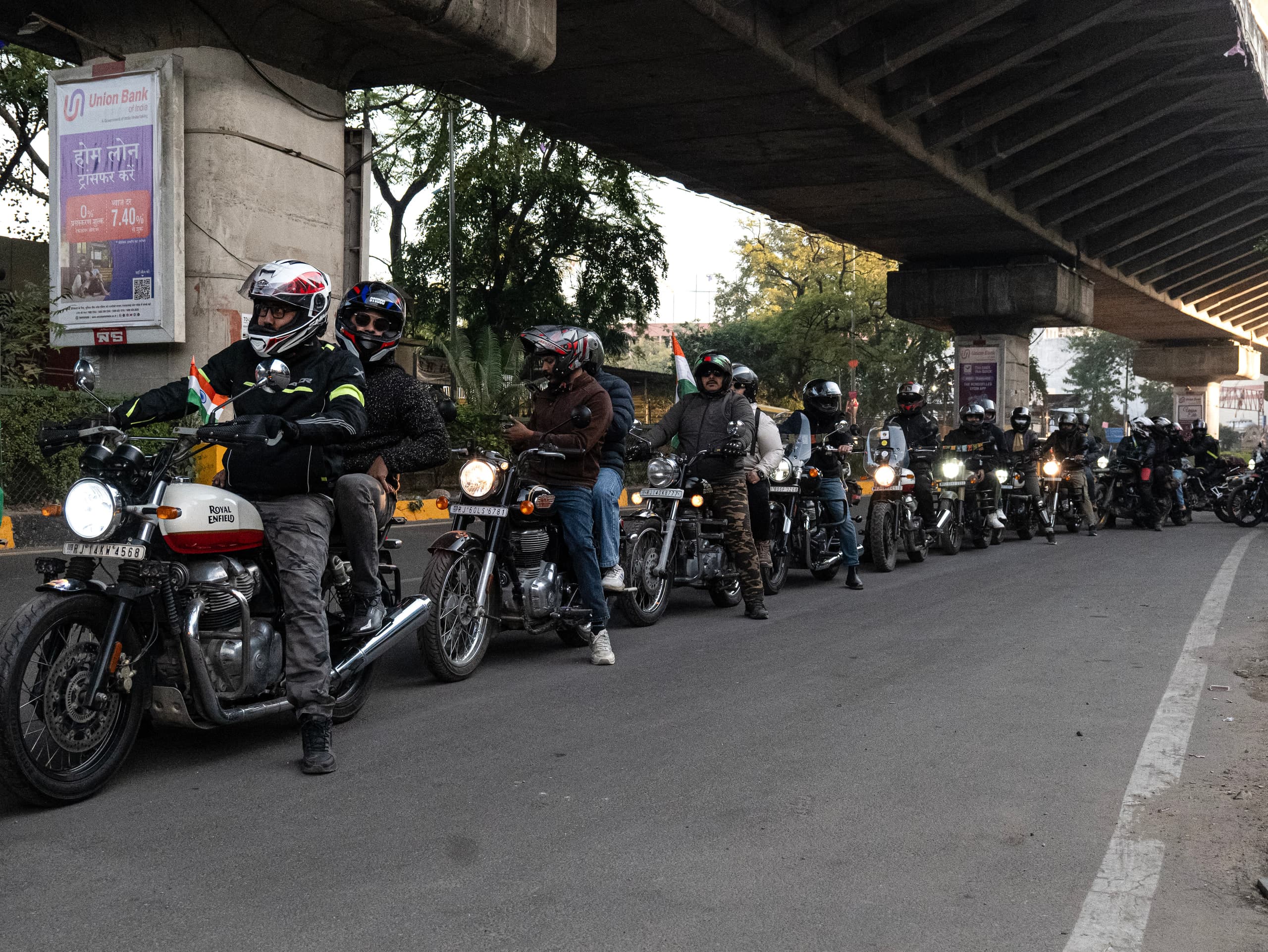 A line of motorcycles waiting under a flyover