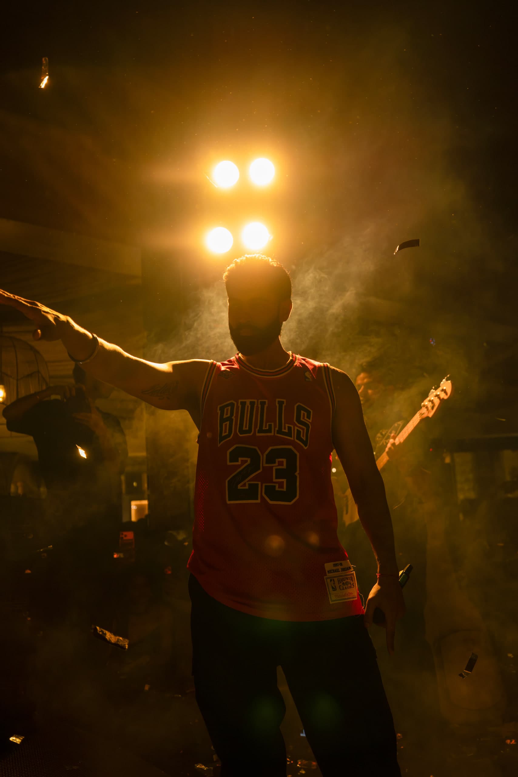 Backlit silhouette against a bank of white lamps, arm outstretched