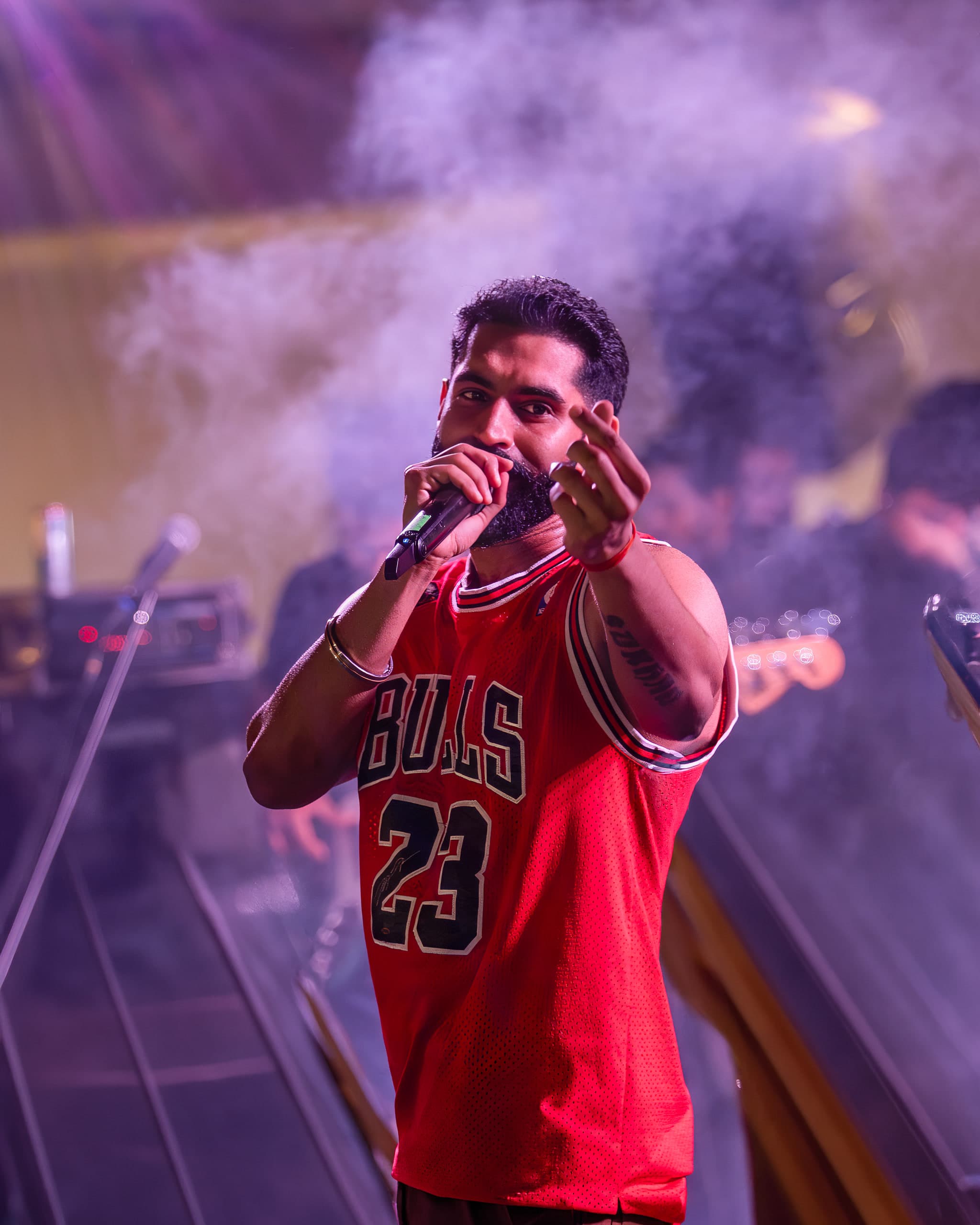 Performer in purple smoke with a hand cupped to the microphone