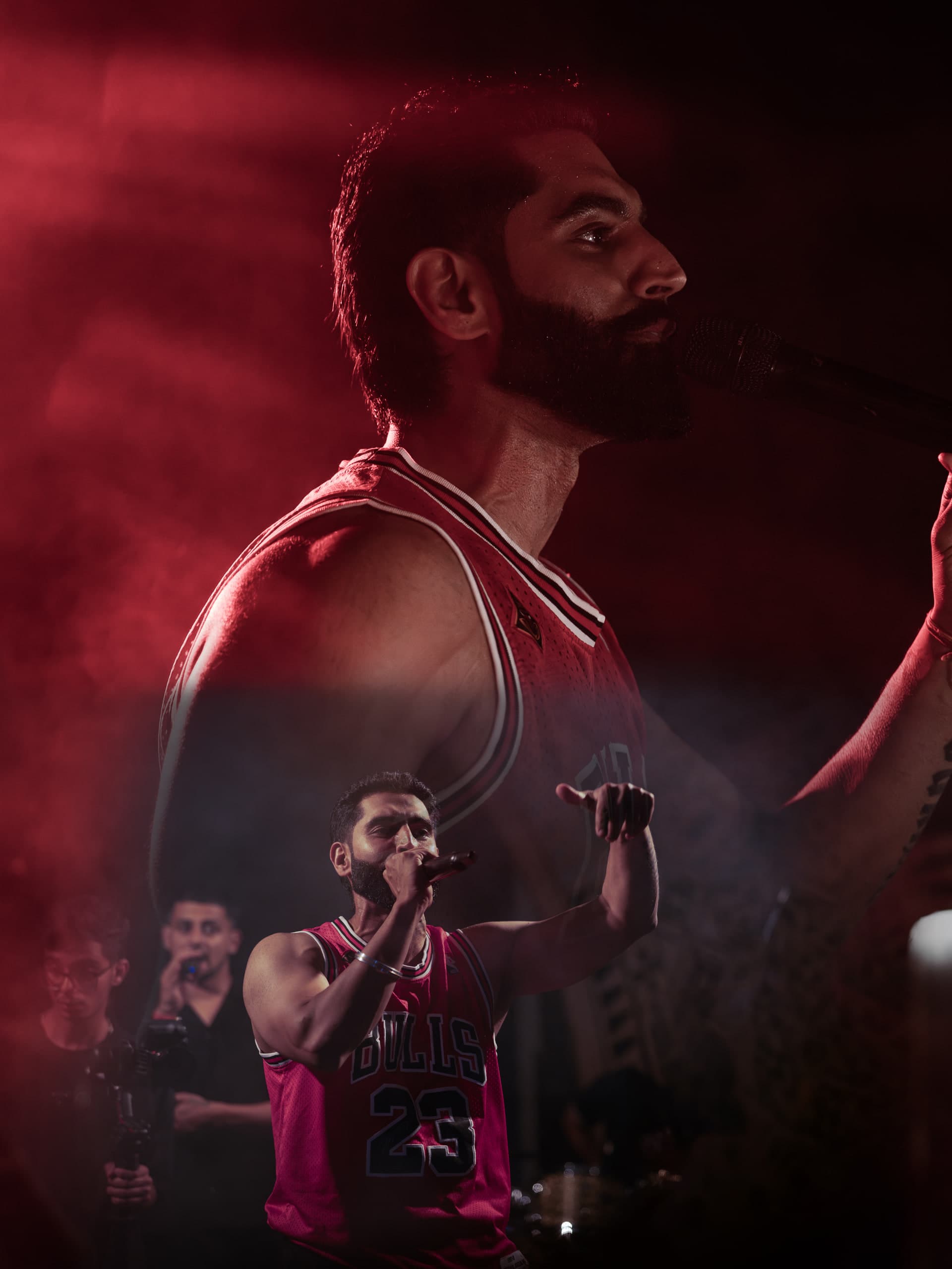 Performer singing under red light, the band playing behind him