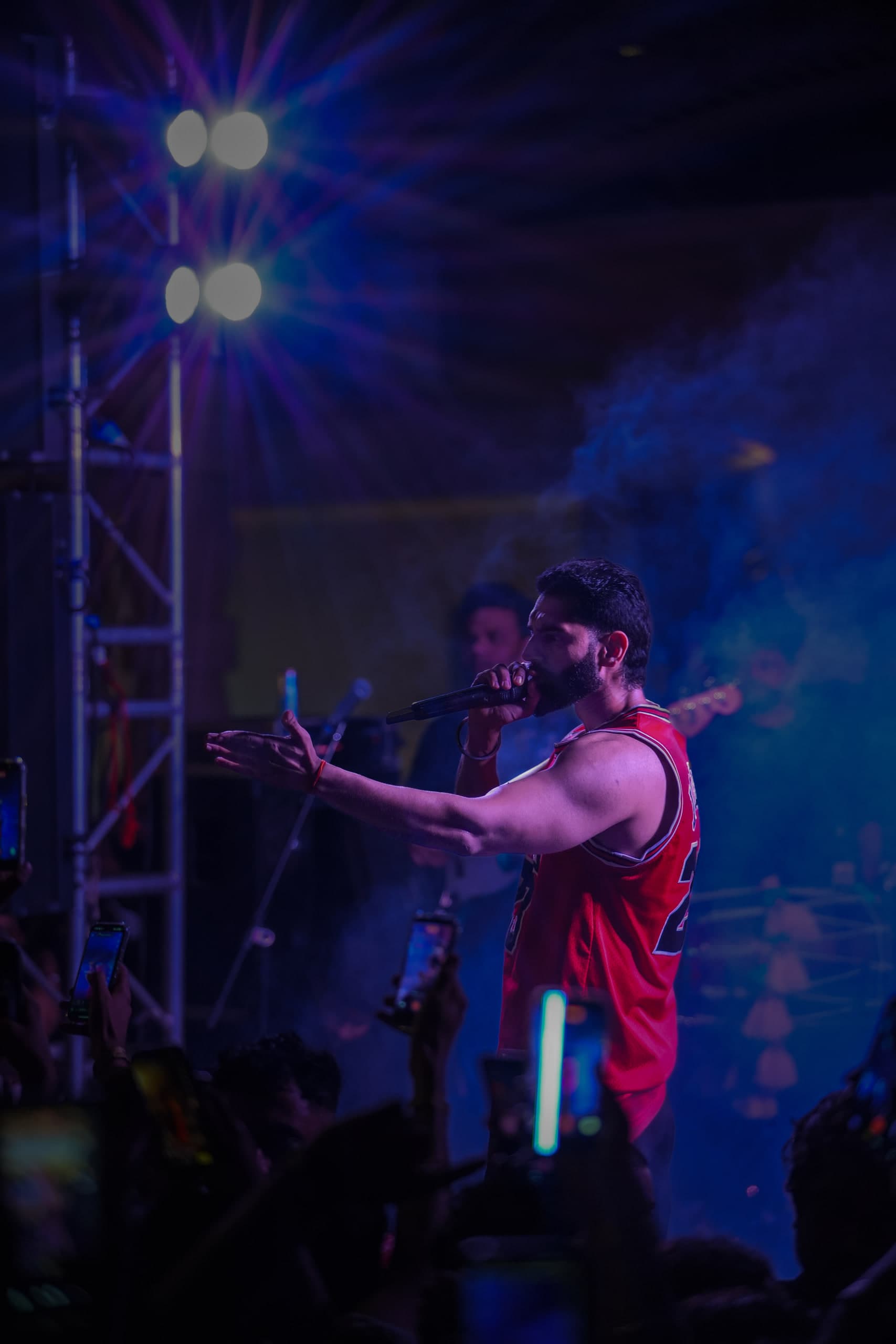 Performer with both arms wide under blue stage lights