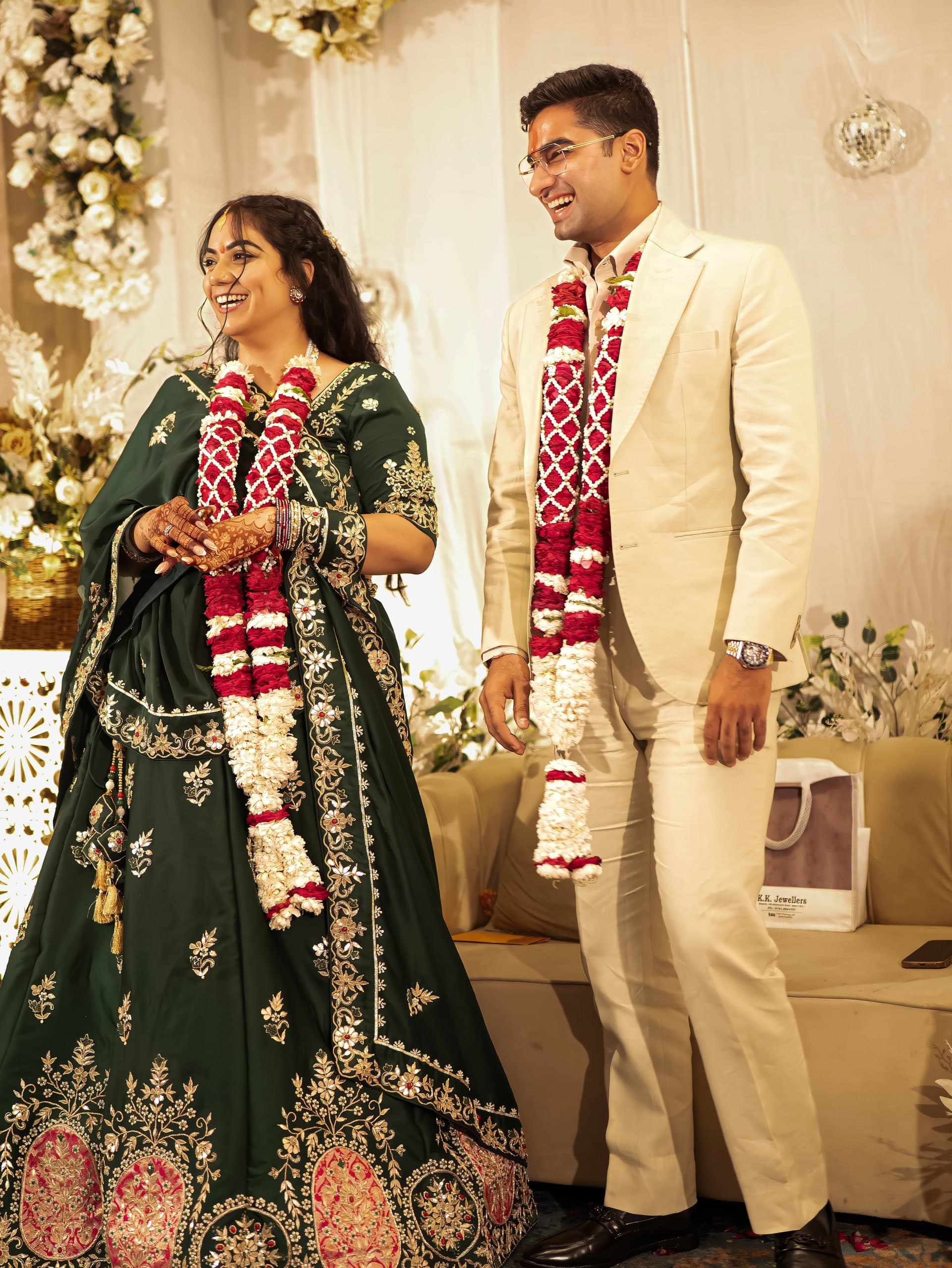 Couple standing together in garlands beneath the floral arch