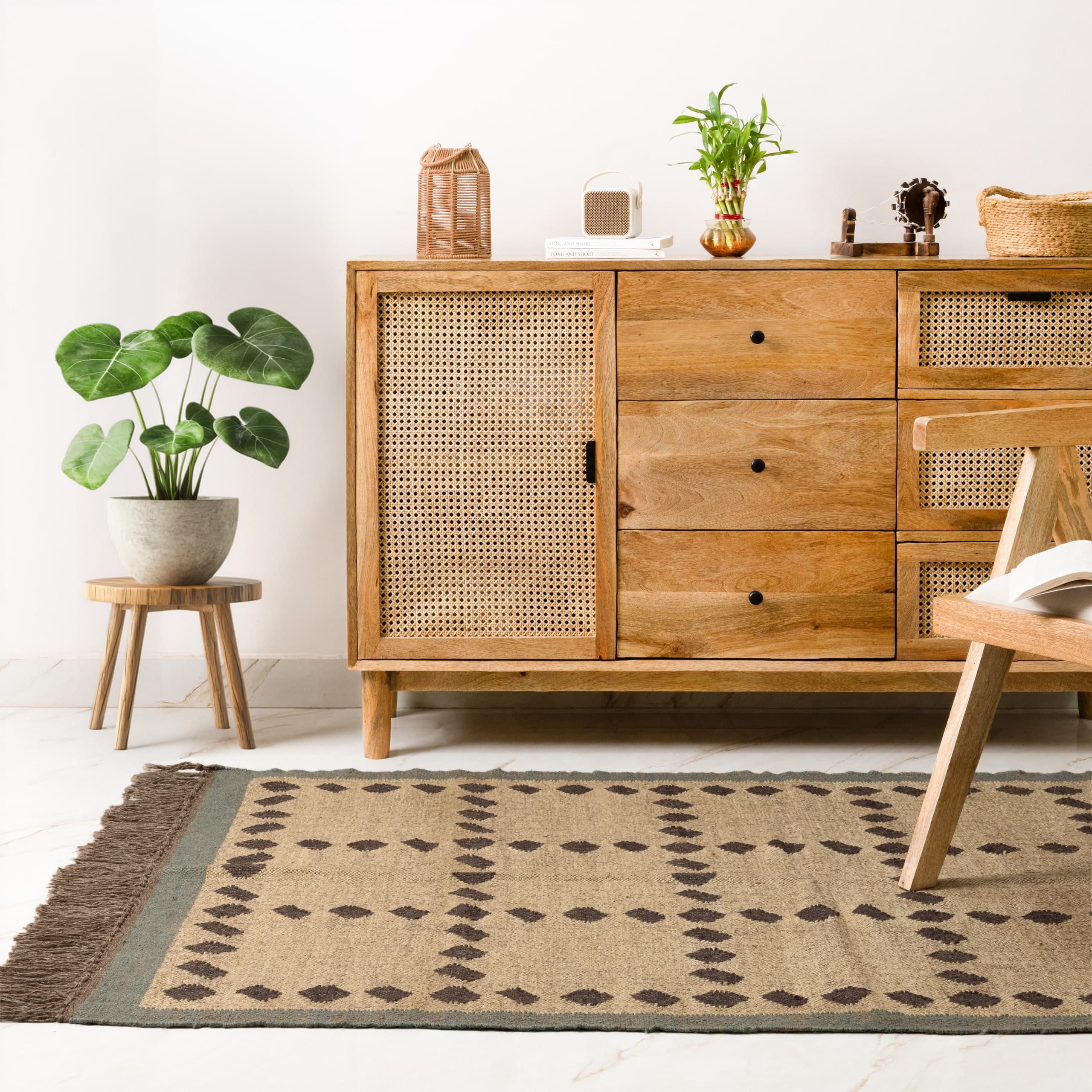 Mango-wood sideboard with cane fronts, a jute rug in front of it and a plant on a low stool