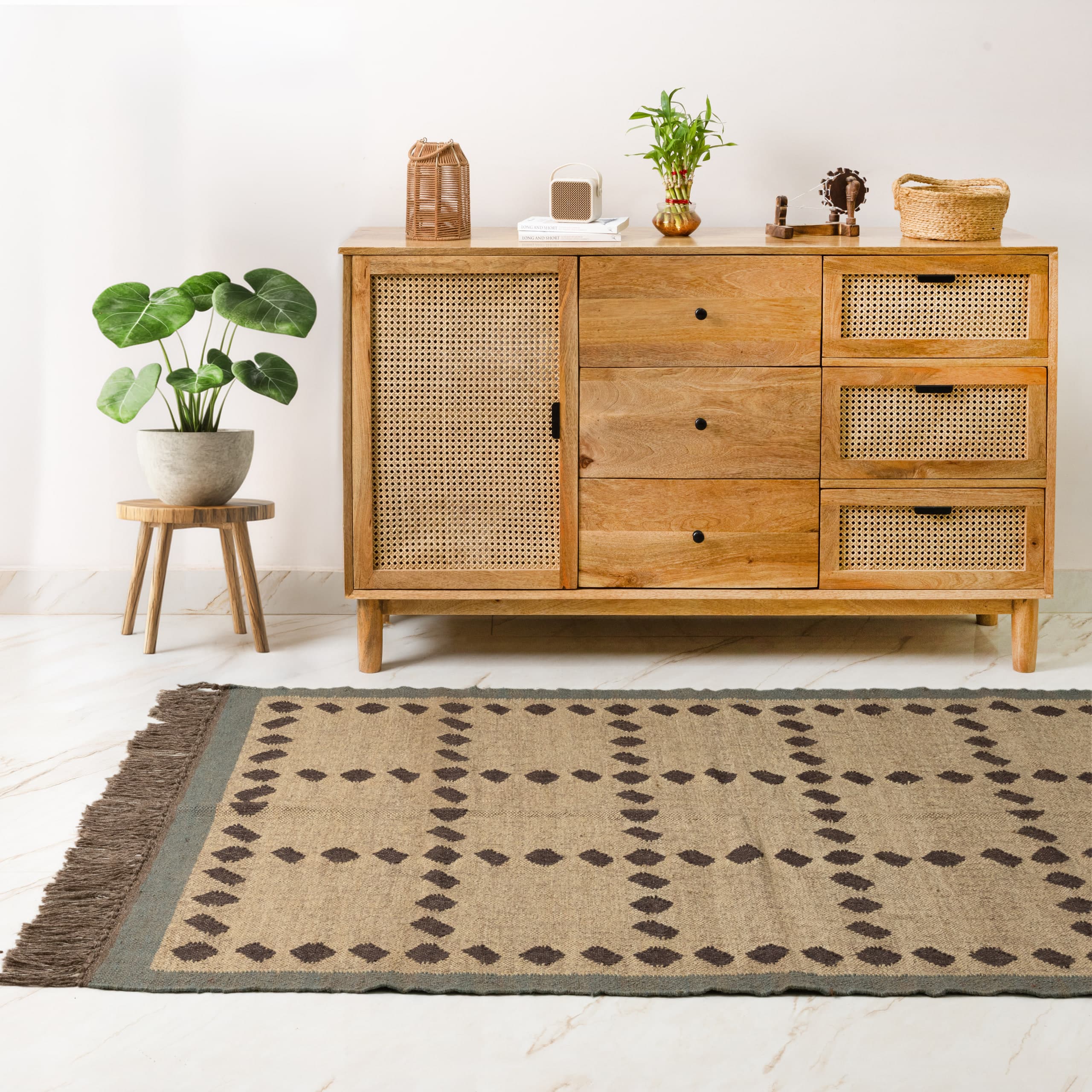 The cane-fronted sideboard square on, patterned jute rug running across the marble floor