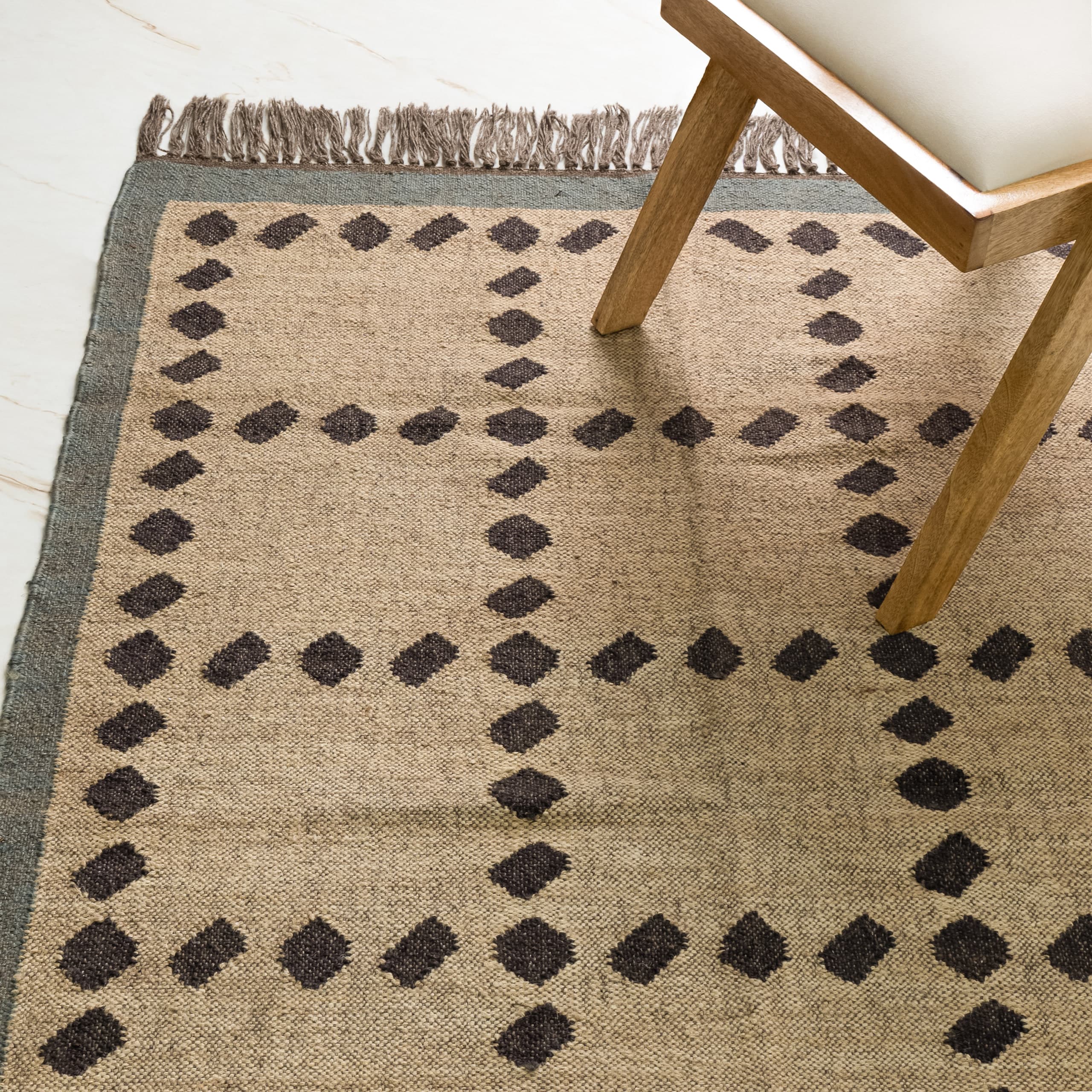 Overhead view of the diamond-patterned jute rug, a chair leg entering at the top right