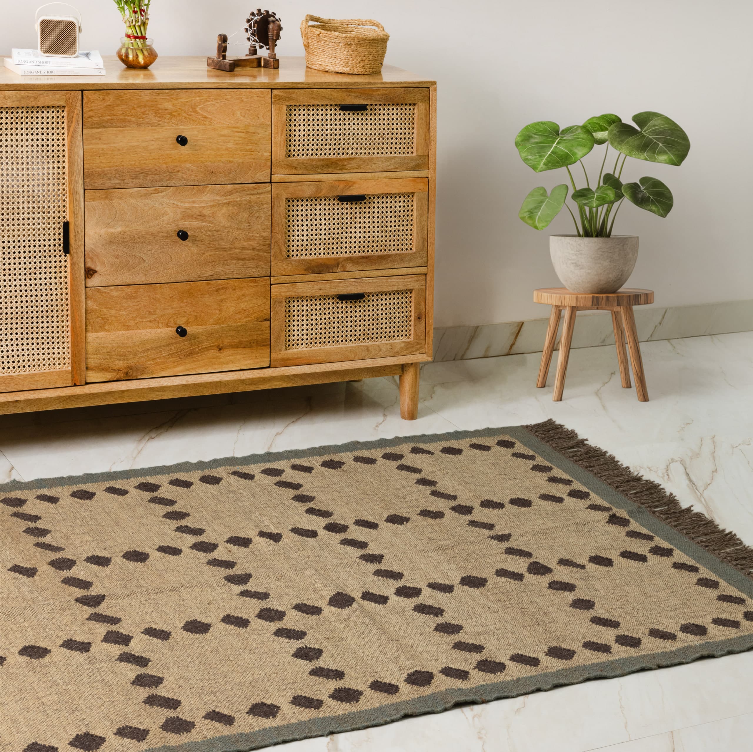 Rug laid out in front of the cane sideboard, stool and plant in the corner beyond it