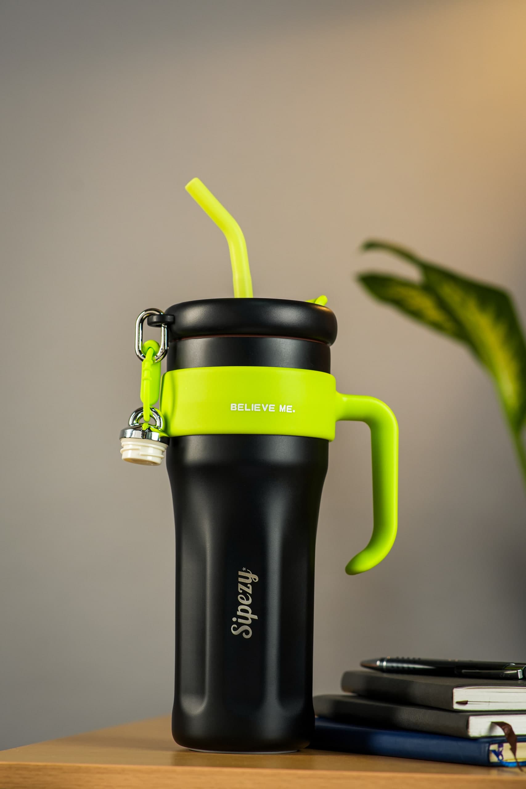 Black tumbler with a lime-green handle on a desk against a warm wall