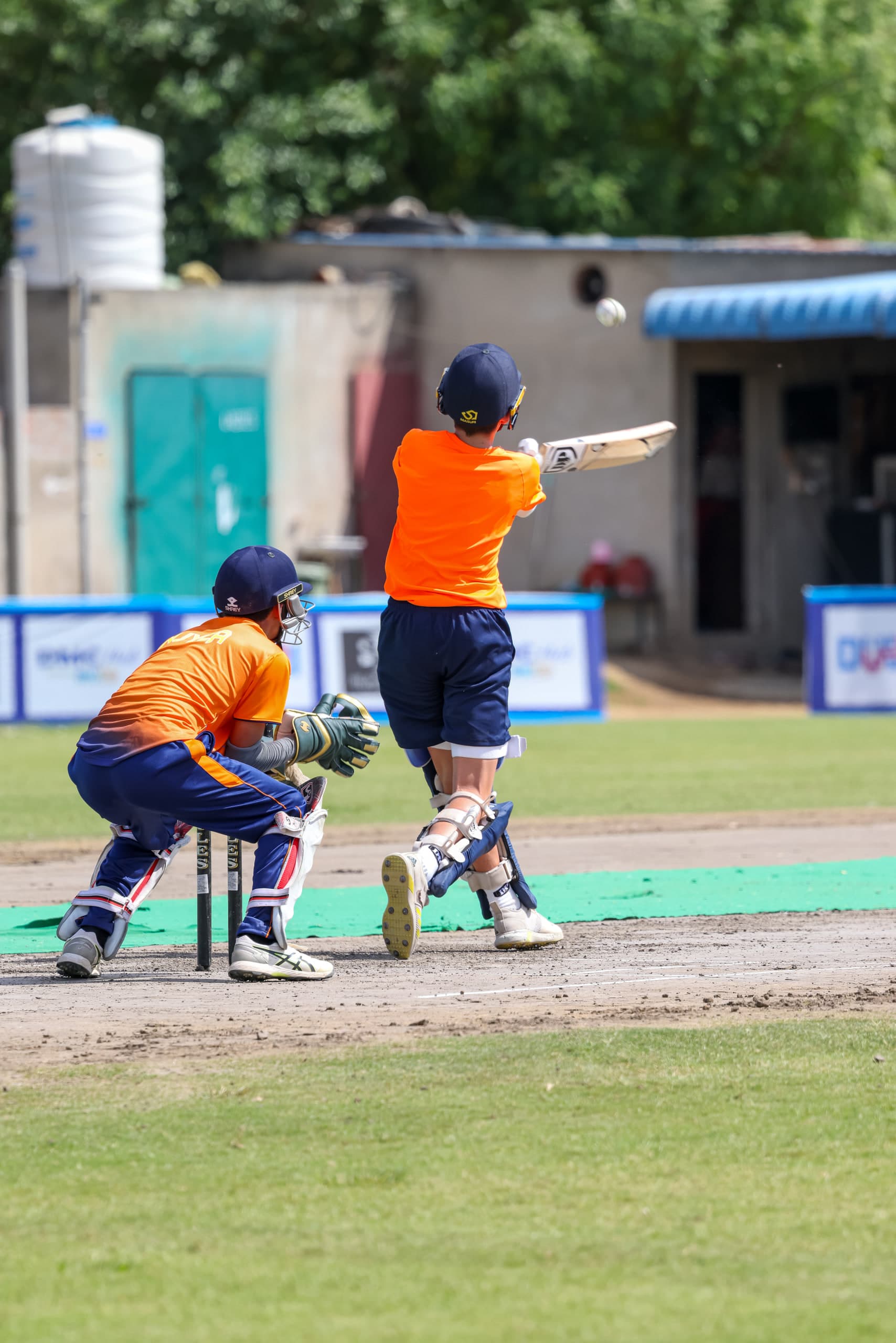 Batter following through as the ball lifts away, wicketkeeper and slip fielder reaching for it
