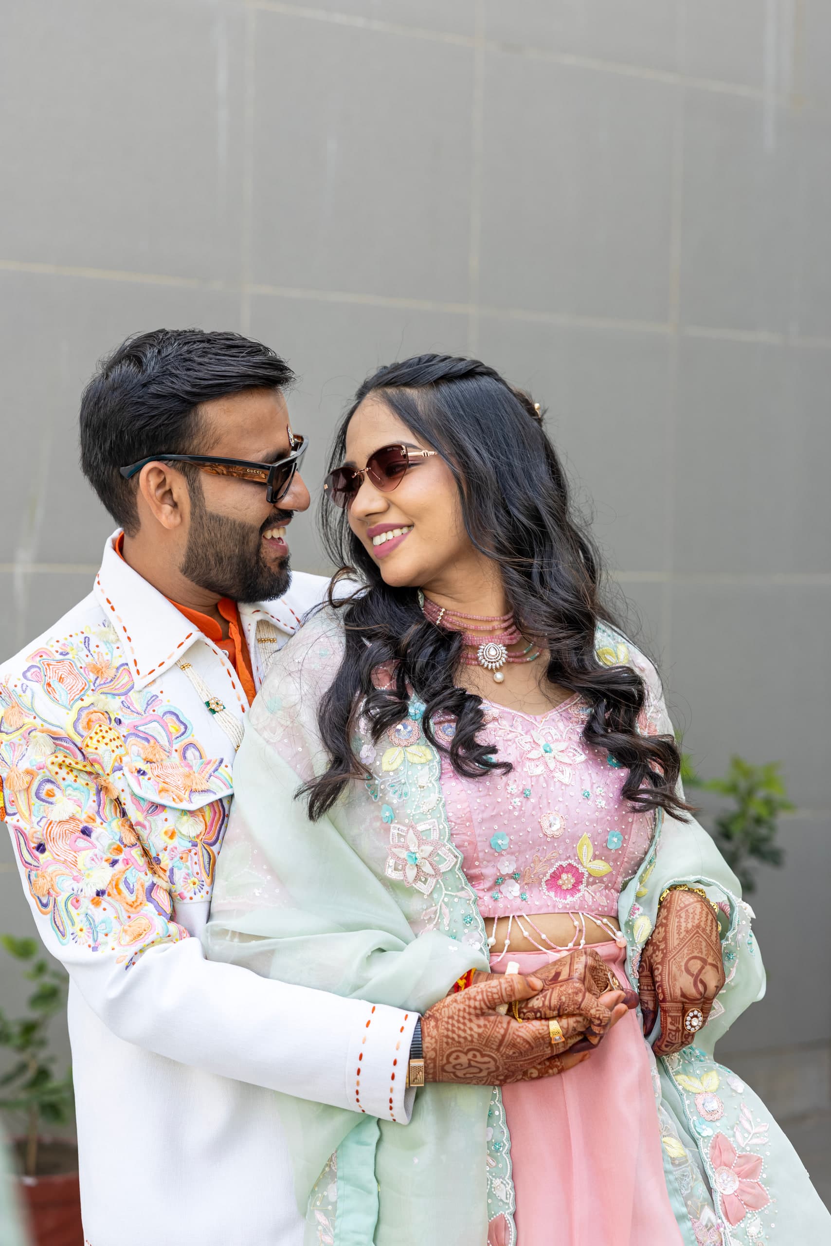 Couple in pale mint and pink, cheek to cheek against a white wall