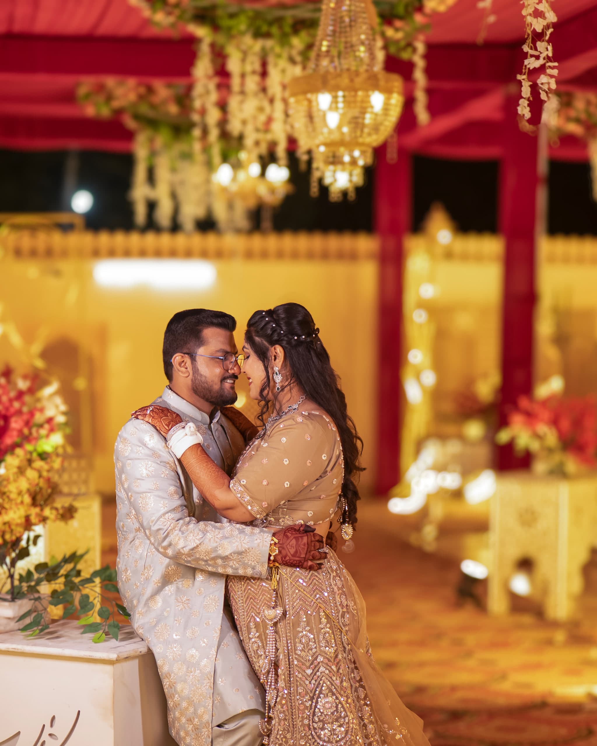Couple embracing in warm gold light under a canopy of flowers