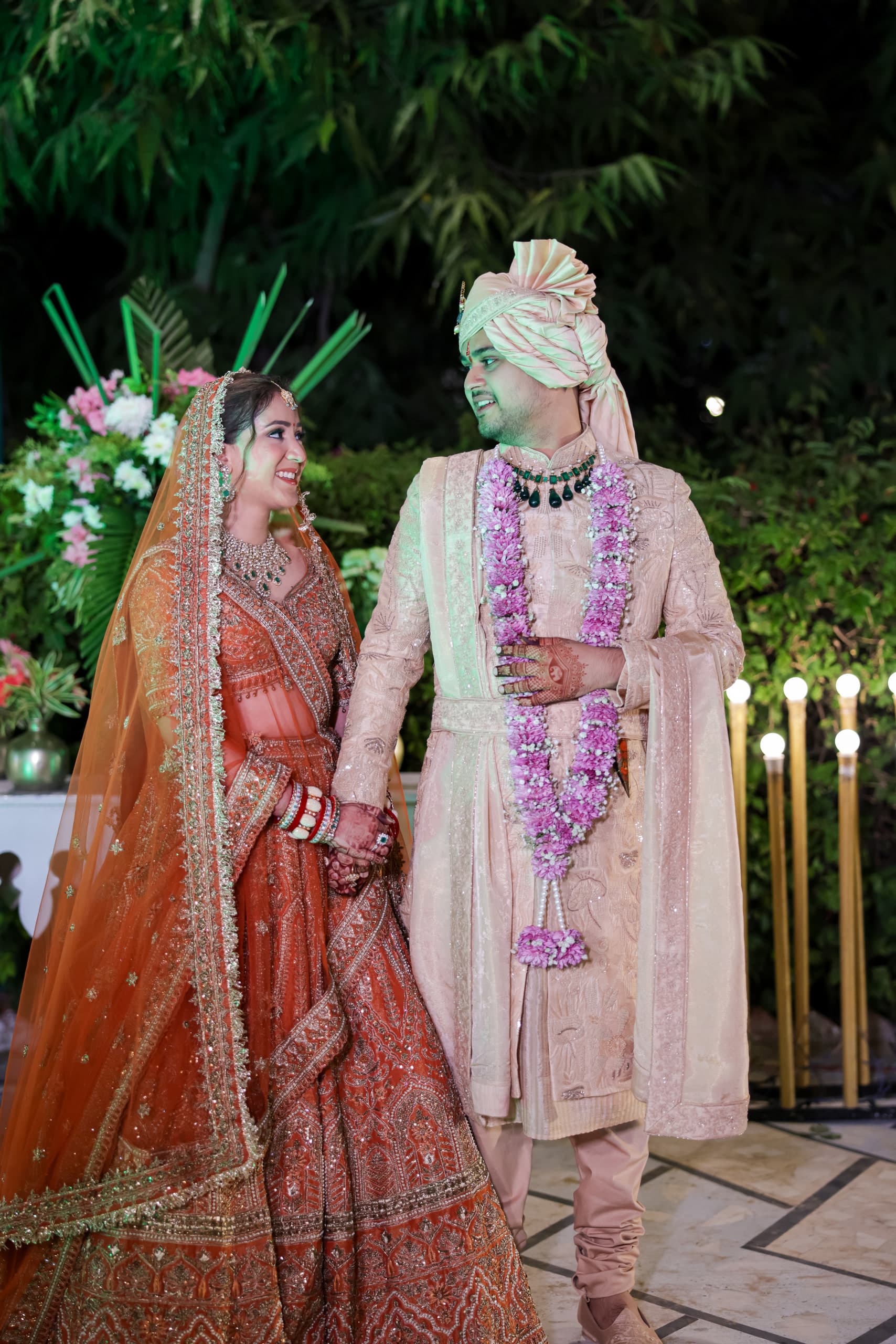 Couple beneath greenery and candlelight, coral and cream